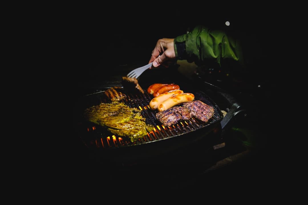 A hand turning and basting meat over the grill
