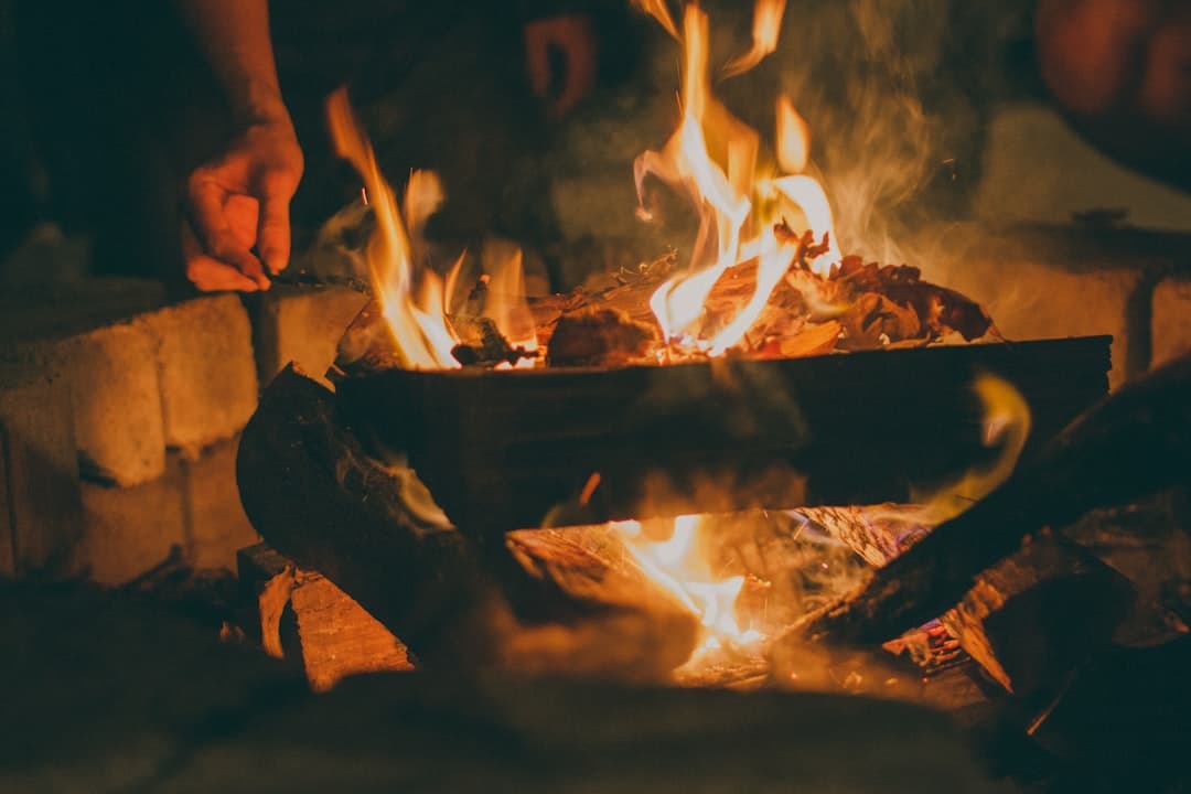 A hand feeding mesquite wood into the fire